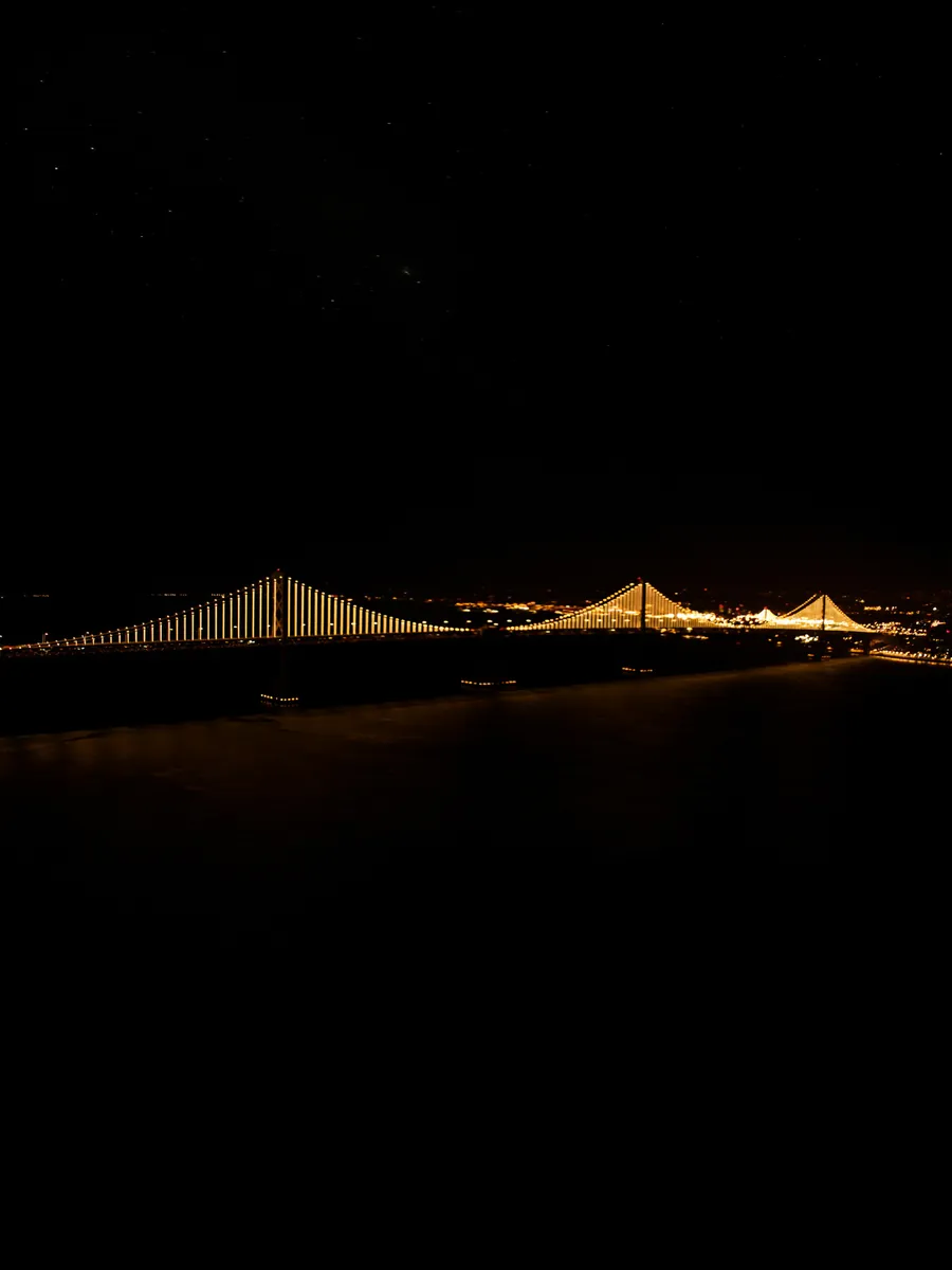 Luces del Bay Bridge reflejadas en el agua de noche, bahía de San Francisco